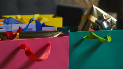 Close-Up-Of-Gift-Wrapped-Presents-In-Colourful-Bags-With-Tag-On-Table-In-Lounge-At-Home